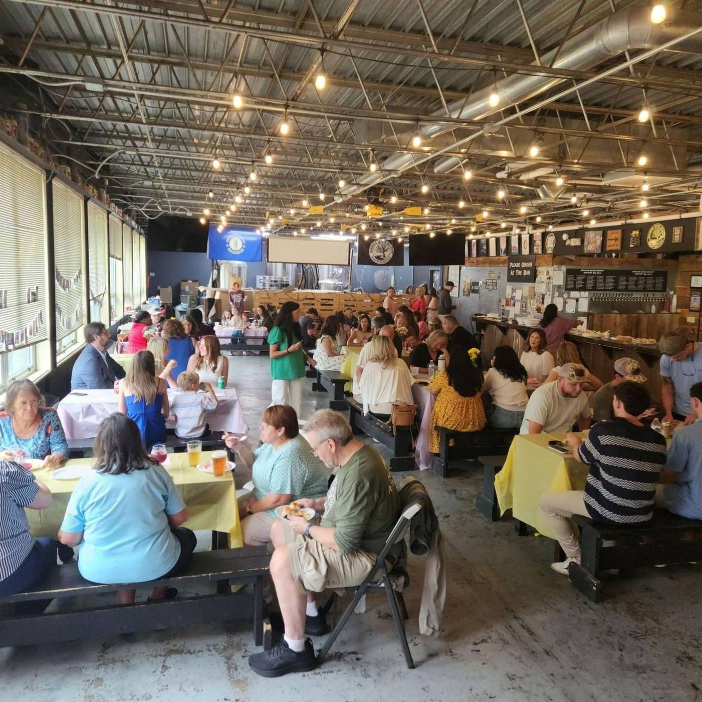 The Dreaming Creek taproom, full of people at long benches under strings of lights
